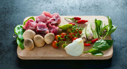 Tomatoes and meat on cutting board over table