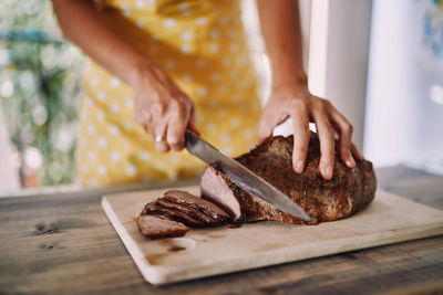 Midsection of man cutting cheese on table