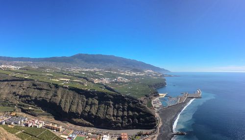 Panoramic view of sea and mountains against clear blue sky