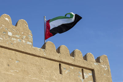 Low angle view of flags against clear blue sky