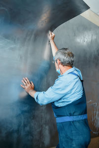 Rear view of man standing against wall