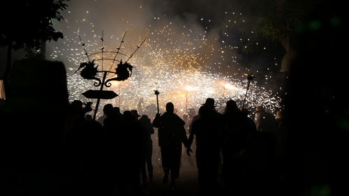 Silhouette people watching firework display at night