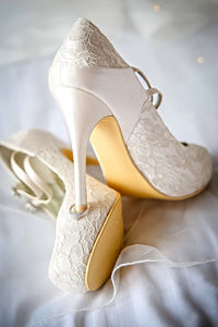 Close-up of white high heels on wedding dress
