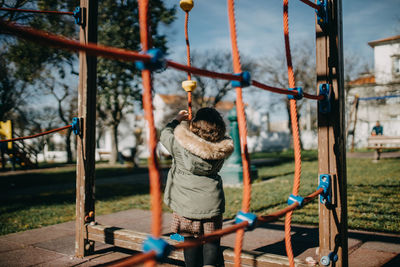 Rear view of girl playing on jungle gym at park