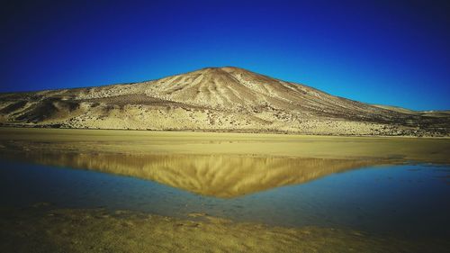 Scenic view of desert against clear blue sky