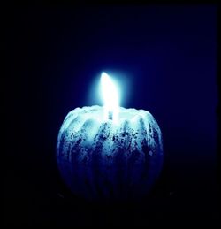Close-up of lit candle in dark room