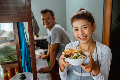 Portrait of smiling woman having food at home