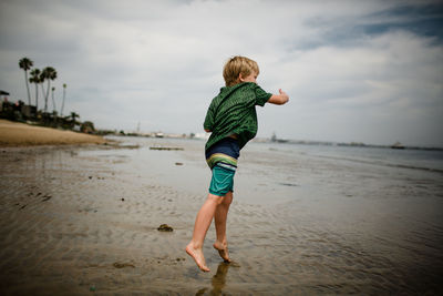 Full length of boy on beach against sky