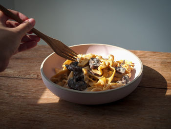 Cropped hand of person preparing food in bowl on table