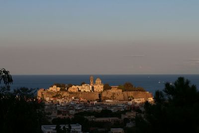 Cityscape by sea against clear sky