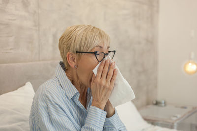 Mature woman suffering from cold and flu at home