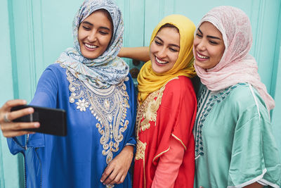 Smiling woman wearing hijab taking selfie outdoors