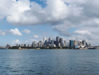 Sea by buildings against sky in city