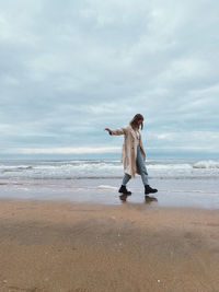 Woman standing at beach against sky and sea