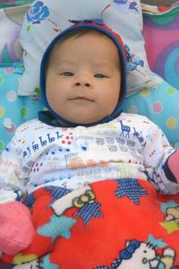 Portrait of cute baby girl lying on bed