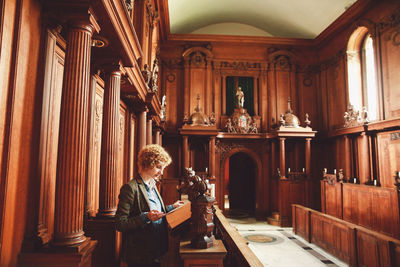 Young woman reading bible while standing in church