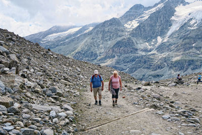 Mature hiking couple walking on dirt road at pasterze glacier against mountains