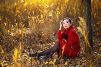 Portrait of woman sitting on field in forest