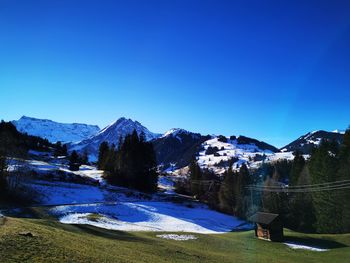 Scenic view of snowcapped mountains against clear blue sky