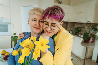 A heartwarming moment. non-binary daughter presents birthday flowers to mother