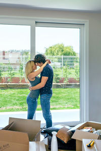 Full length of young woman standing against window