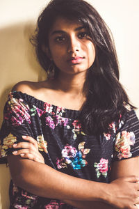 Portrait of beautiful young woman standing against wall