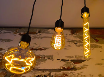 Close-up of illuminated light bulb hanging at night