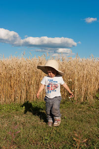 Boy standing on field against sky