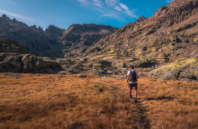 Rear view of man walking on mountain against sky