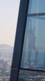 Low angle view of cityscape against sky seen through glass window