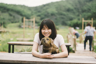 Portrait of smiling woman with dog statue sitting at picnic table 