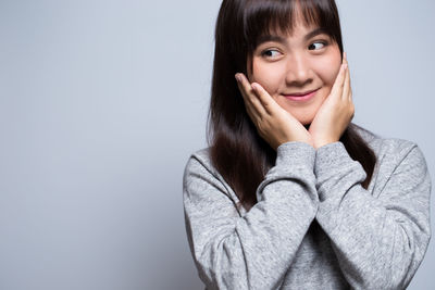 Smiling young woman against gray background