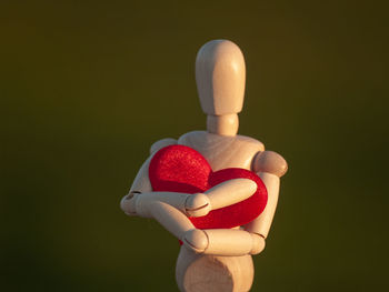 Close-up of wooden figurine with heart shape against black background