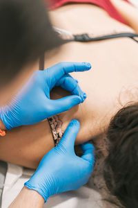 Closeup of crop anonymous therapist inserting needles in back of patient and helping relieving pain with acupuncture method