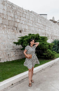 Full length of woman standing against wall