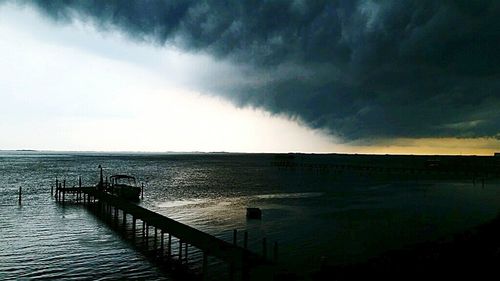 Pier on sea against cloudy sky