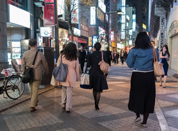 Rear view of people walking on street in city