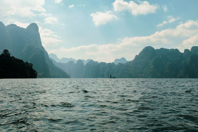 Scenic view of sea by mountains against sky