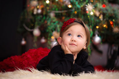 Portrait of cute baby girl in illuminated christmas tree