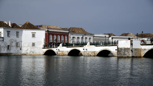 Arch bridge over river against buildings in city against clear sky