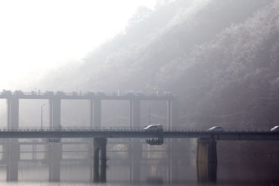 Cars on bridge over canal during foggy weather