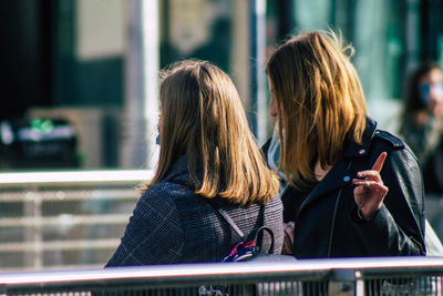 Rear view of woman using mobile phone outdoors