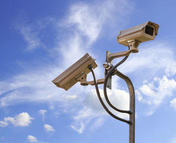Low angle view of security camera against sky