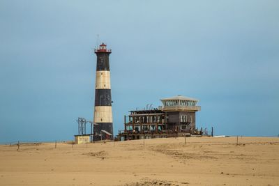 Lighthouse on beach against clear sky