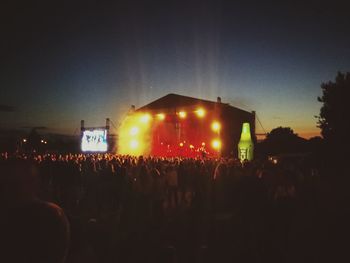 Crowd at music concert against sky at night