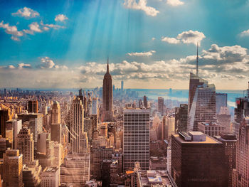 Aerial view of city buildings against cloudy sky