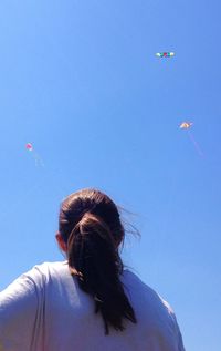 Low angle view of girl flying a kite against clear blue sky