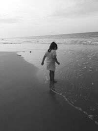 Full length of girl standing on beach against sky