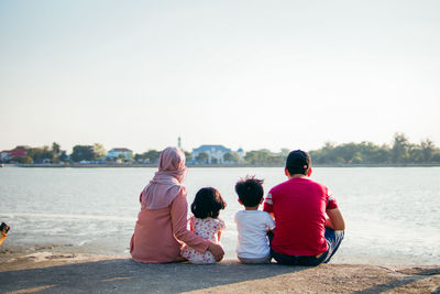 Rear view of people looking at sea against clear sky