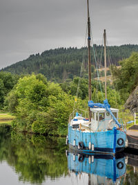 Boat moored in calm lake against sky